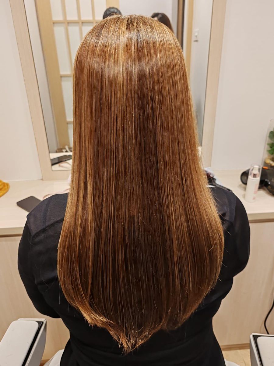 Long, glossy honey-toned hair after a keratin treatment